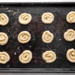 Unbaked cookies lined up on a baking sheet.