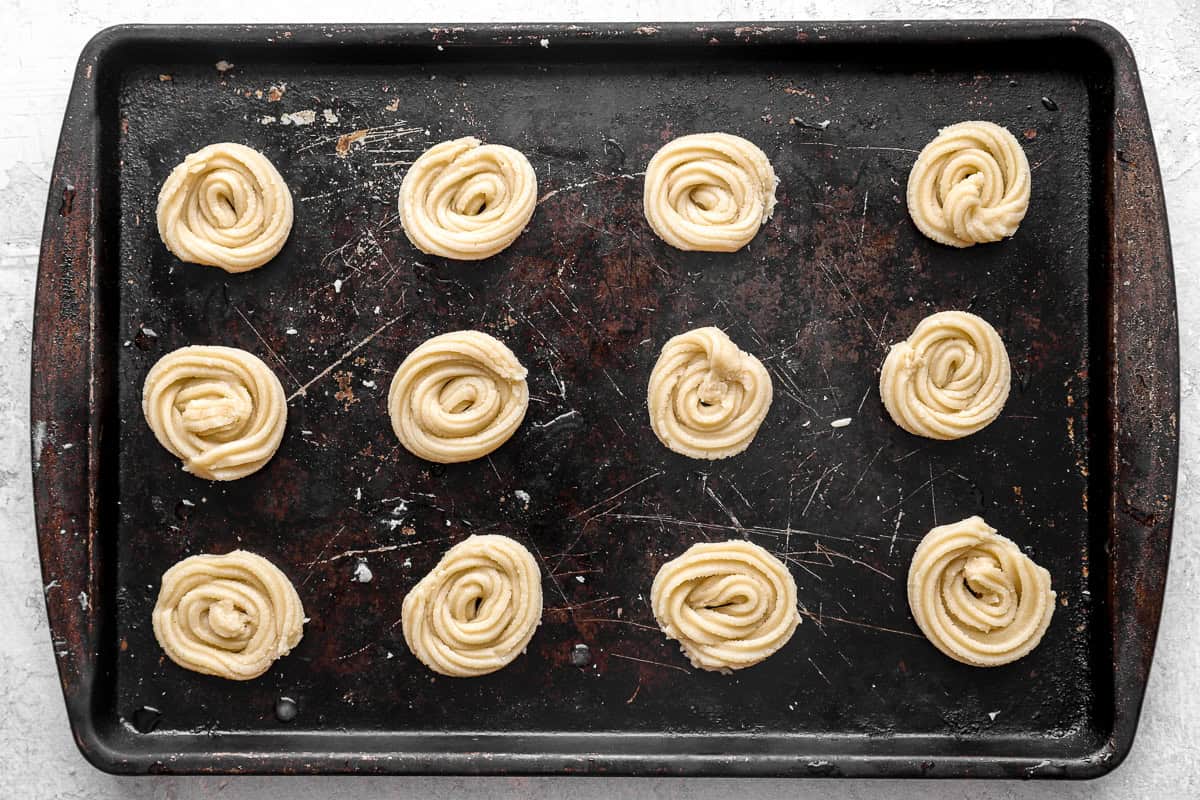 Unbaked cookies lined up on a baking sheet.