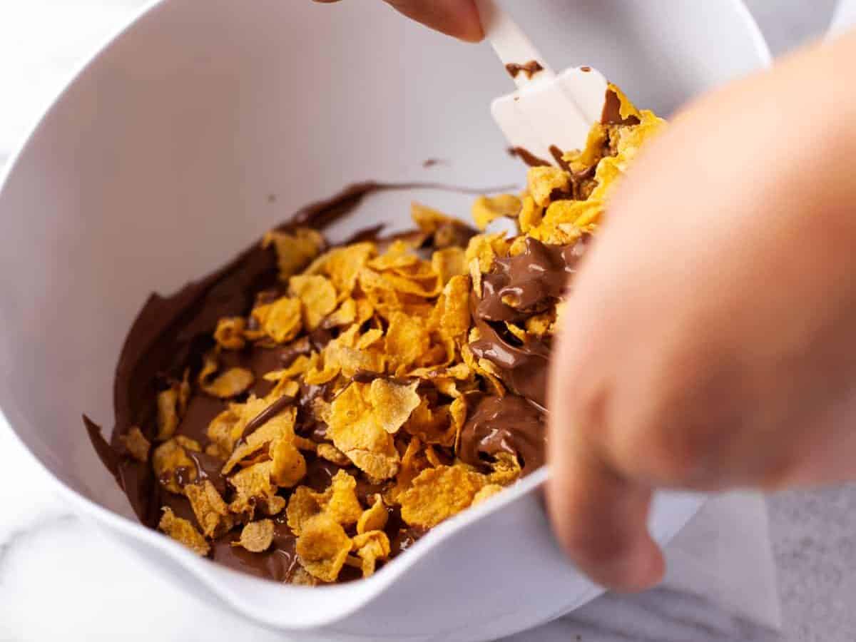 Mixing cornflakes with chocolate.