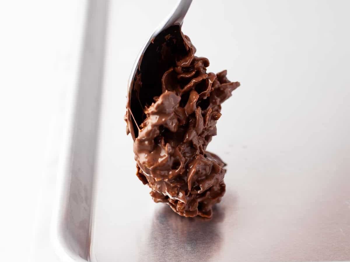 Dropping chocolate-coated cornflake cookie batter onto a baking tray.