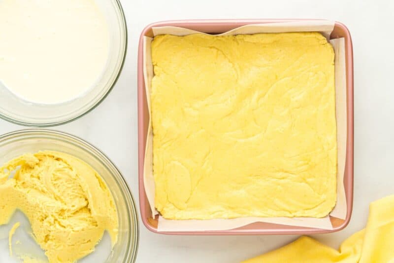 thick lemon cake batter pressed into the bottom of a square baking pan.