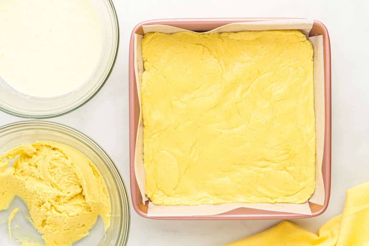 thick lemon cake batter pressed into the bottom of a square baking pan.