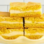 closeup of stacked lemon cake bars on a yellow cake stand.