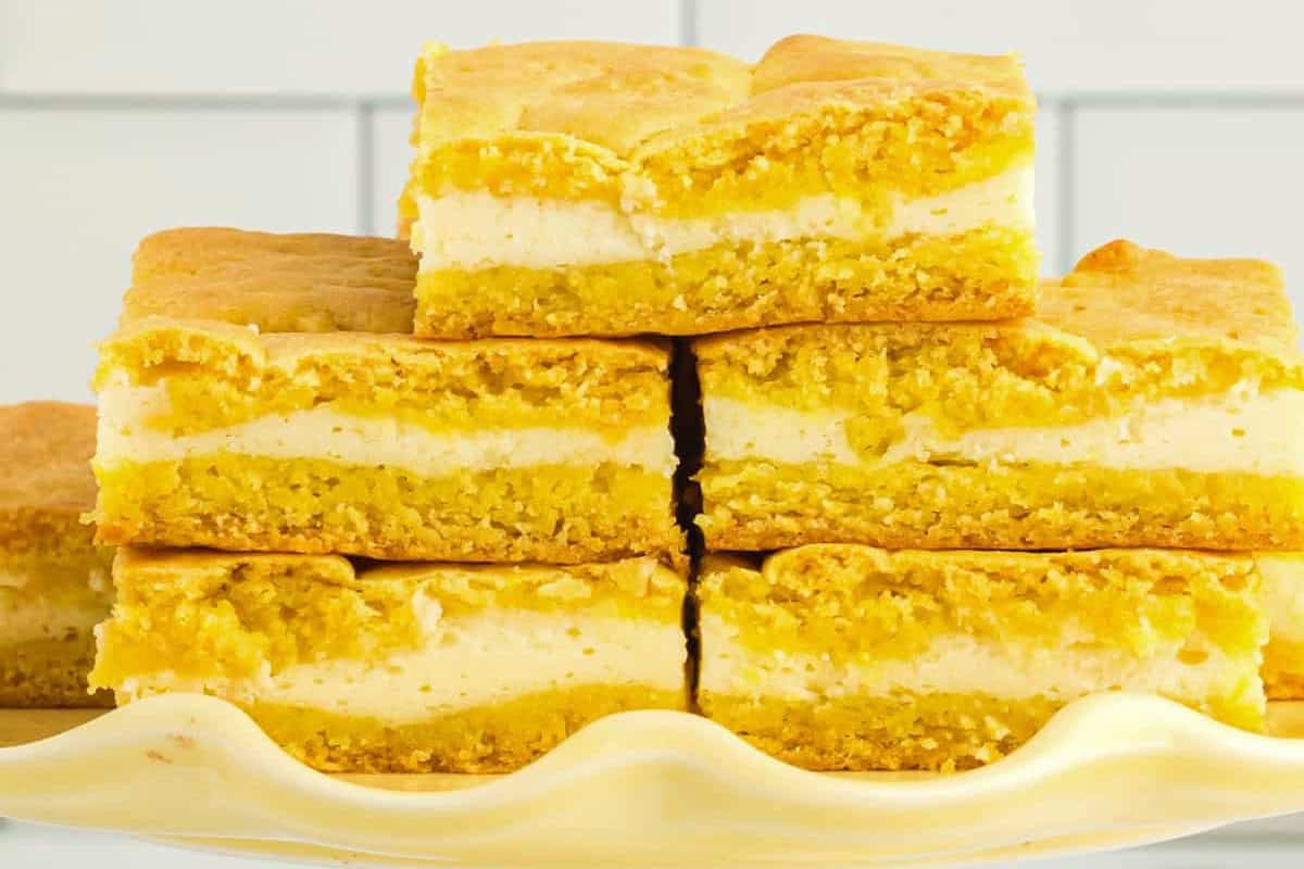 closeup of stacked lemon cake cream cheese cake mix bars on a yellow cake stand.