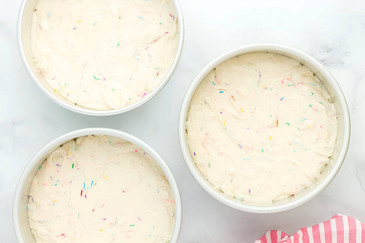 fruity pebbles cake batter in 3 cake pans.