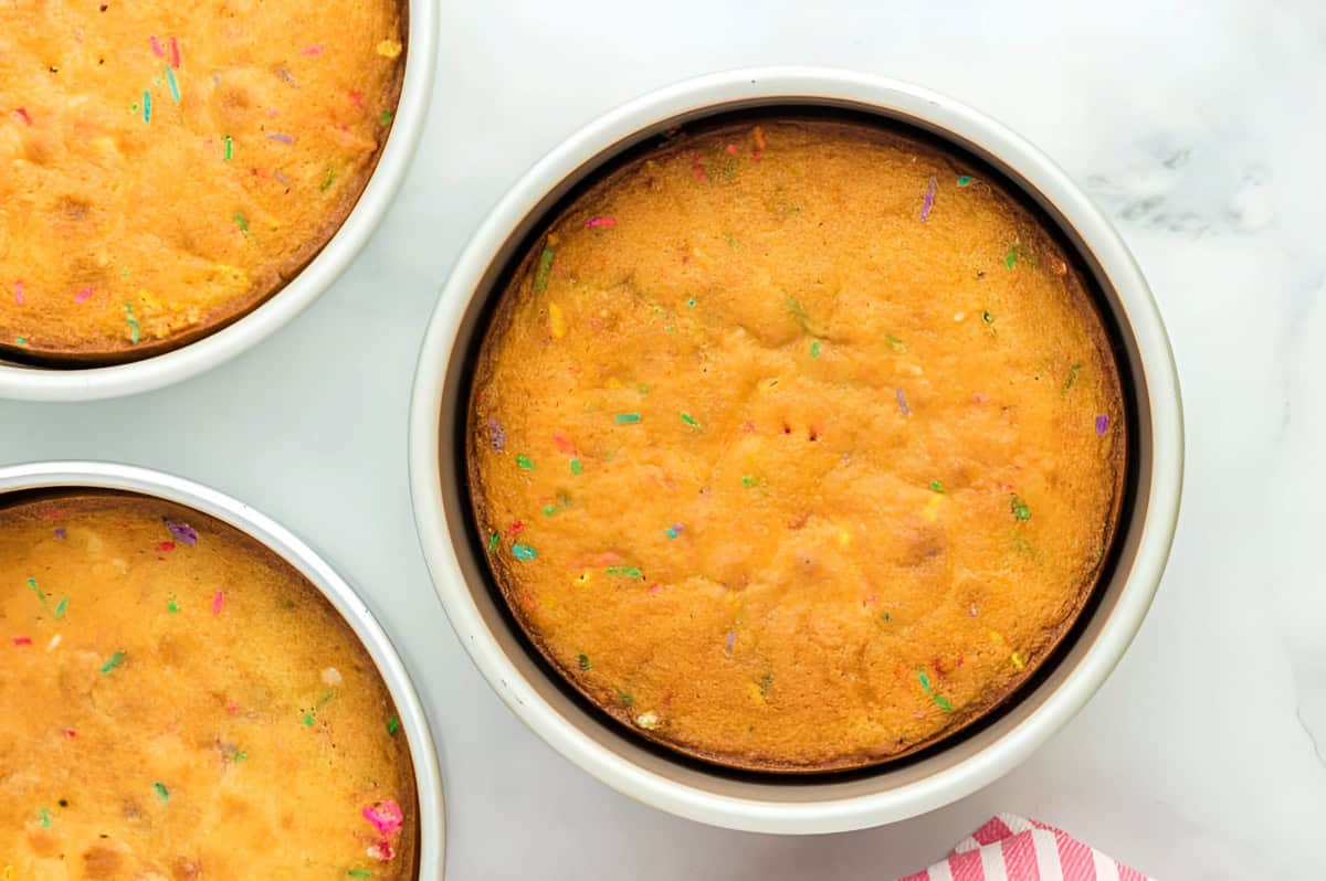 baked funfetti cake layers in cake pans.