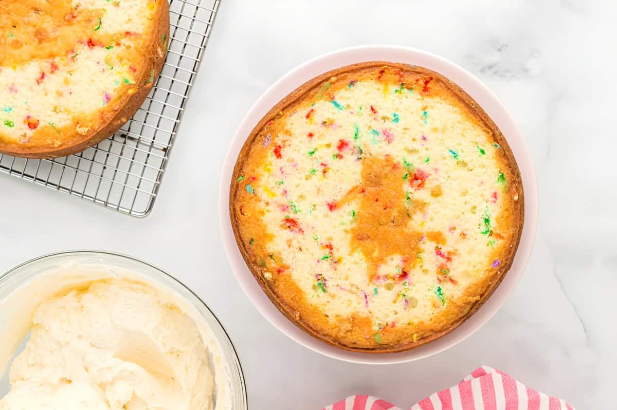 a leveled fruity pebbles cake layer on a cake stand.