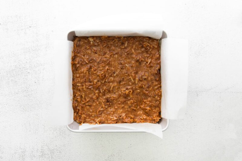 caramel and coconut mixture pressed into a square baking pan.