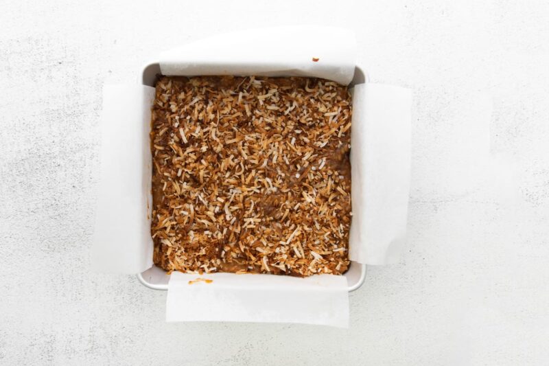 samoa cookie bars in a lined square baking pan.