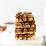 four stacked samoa cookie bars on an overturned baking sheet.