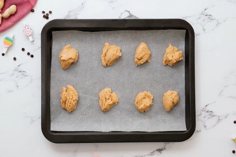 dollops of peanut butter filling on a lined baking sheet.