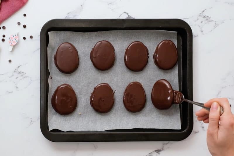 placing chocolate-dipped peanut butter eggs on a lined baking sheet to set.