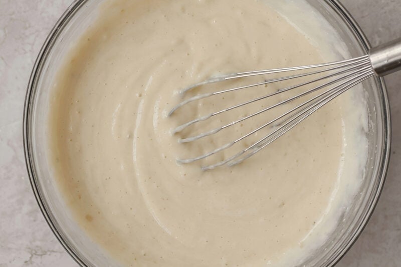 eggless key lime pie filling in a glass bowl with a whisk.