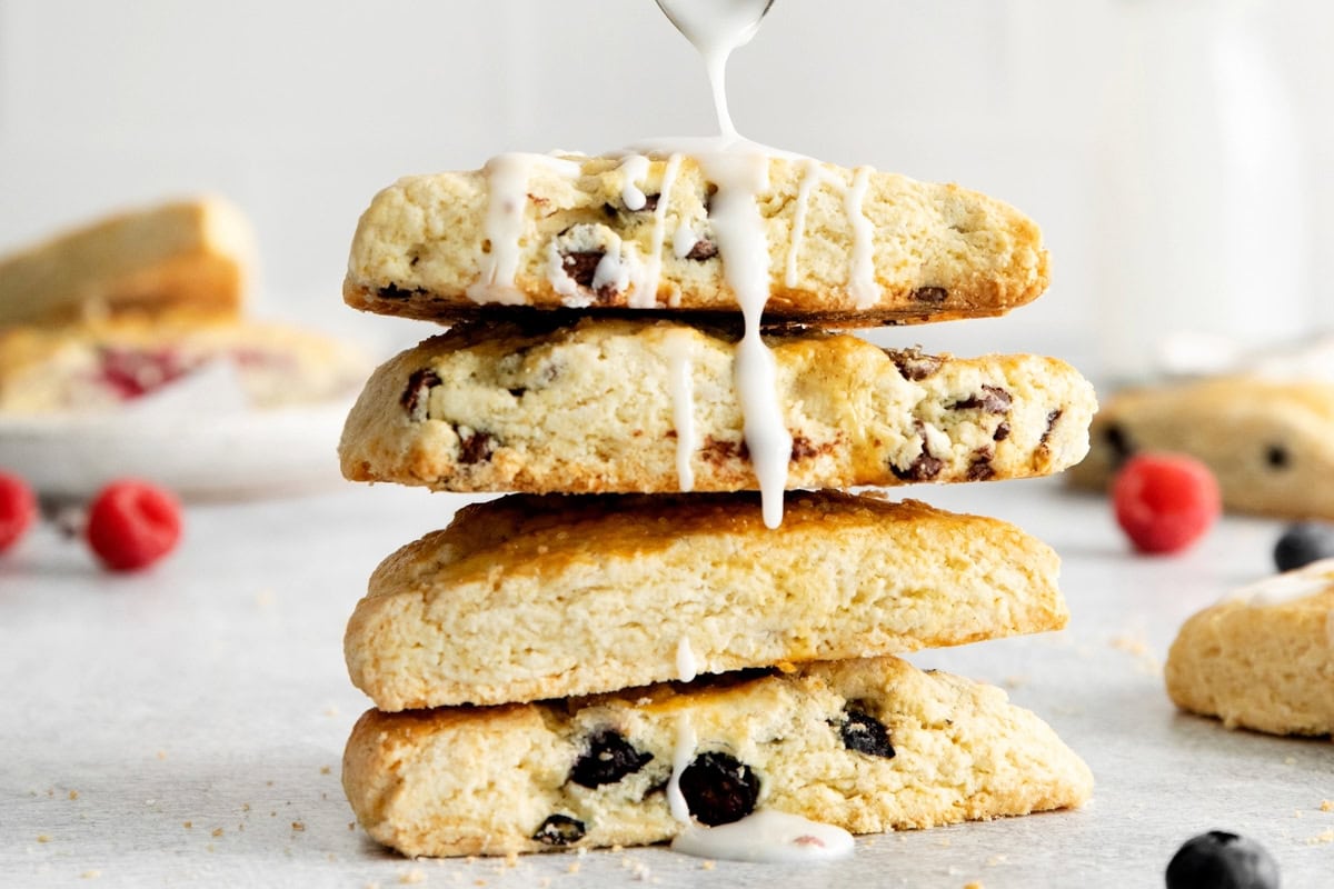 drizzling icing over a four-stack of american scones.
