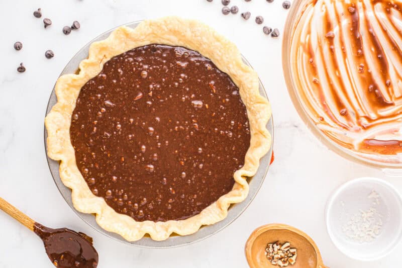 german chocolate pie filling poured over a par-baked pie crust in a pie pan.