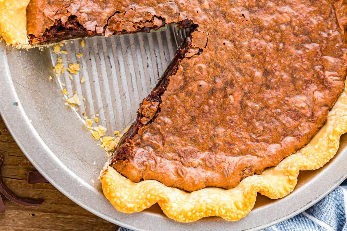 partial overhead view of baked german chocolate pie in a pie pan with a slice removed.