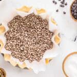 parchment paper and pie weights over a crimped pie crust in a pie pan.