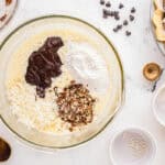 folding chocolate, coconut, pecans, and flour into whipped eggs in a glass bowl.