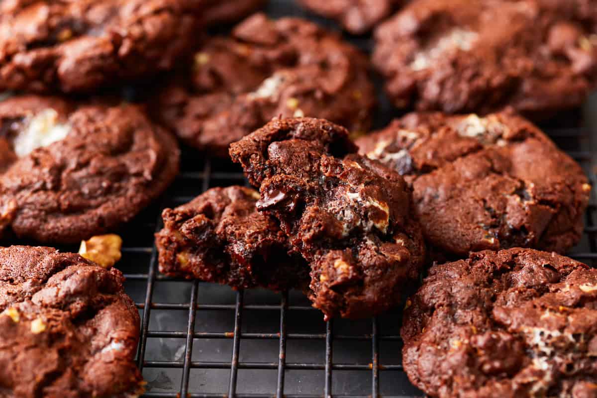 closeup of a bitten rocky road cookie on a wire rack surrounded by cookies.