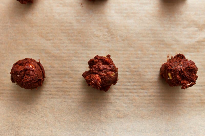 portioned rocky road cookie dough balls on a lined baking sheet.