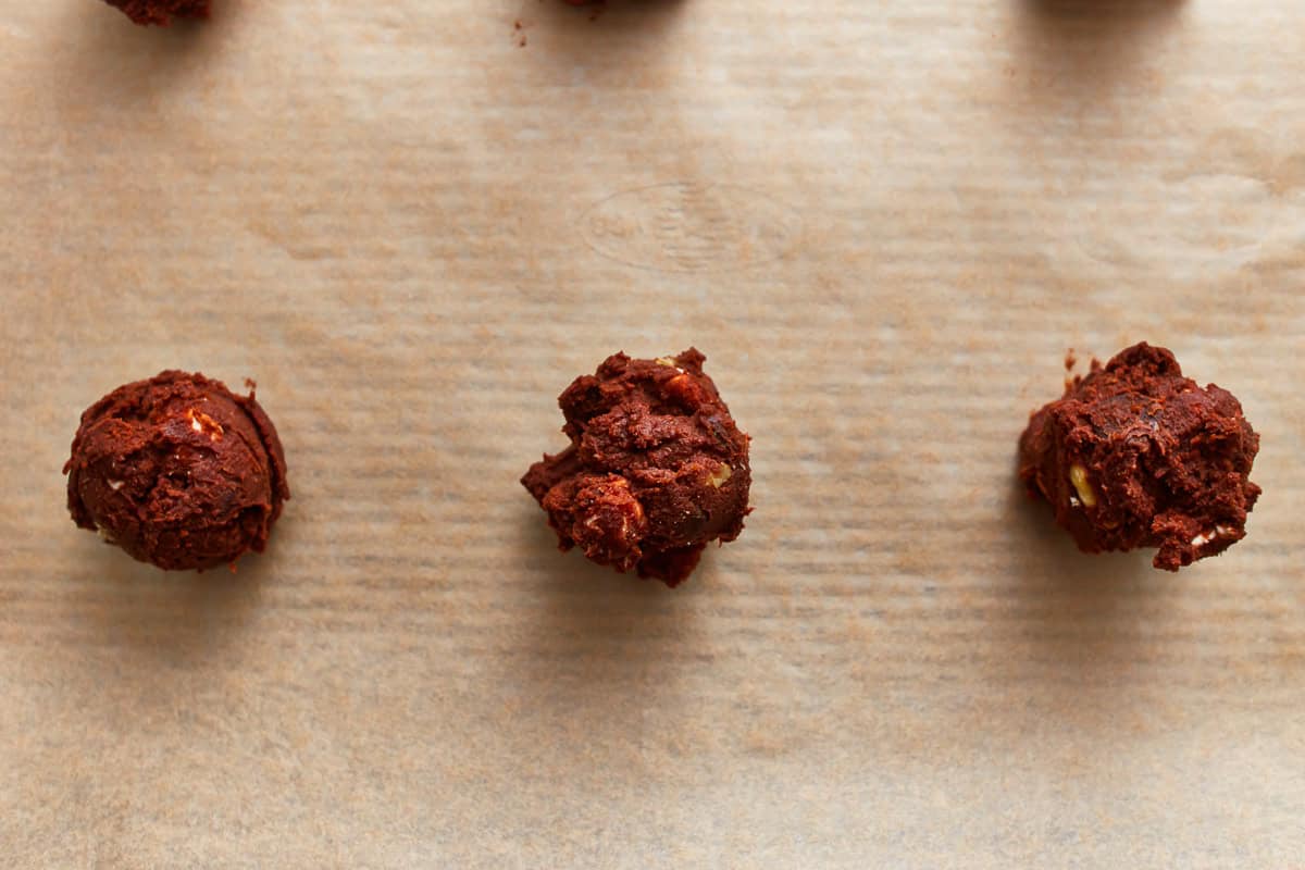 portioned rocky road cookie dough balls on a lined baking sheet.