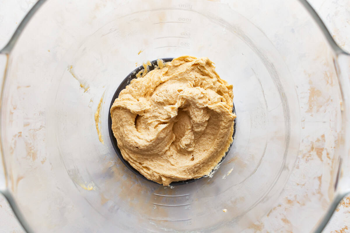 Cookie dough coming together in a glass mixing bowl.