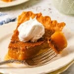 a bite of vinegar pie on a fork resting on a plate with a slice of vinegar pie topped with whipped cream.
