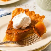 a bite of vinegar pie on a fork resting on a plate with a slice of vinegar pie topped with whipped cream.