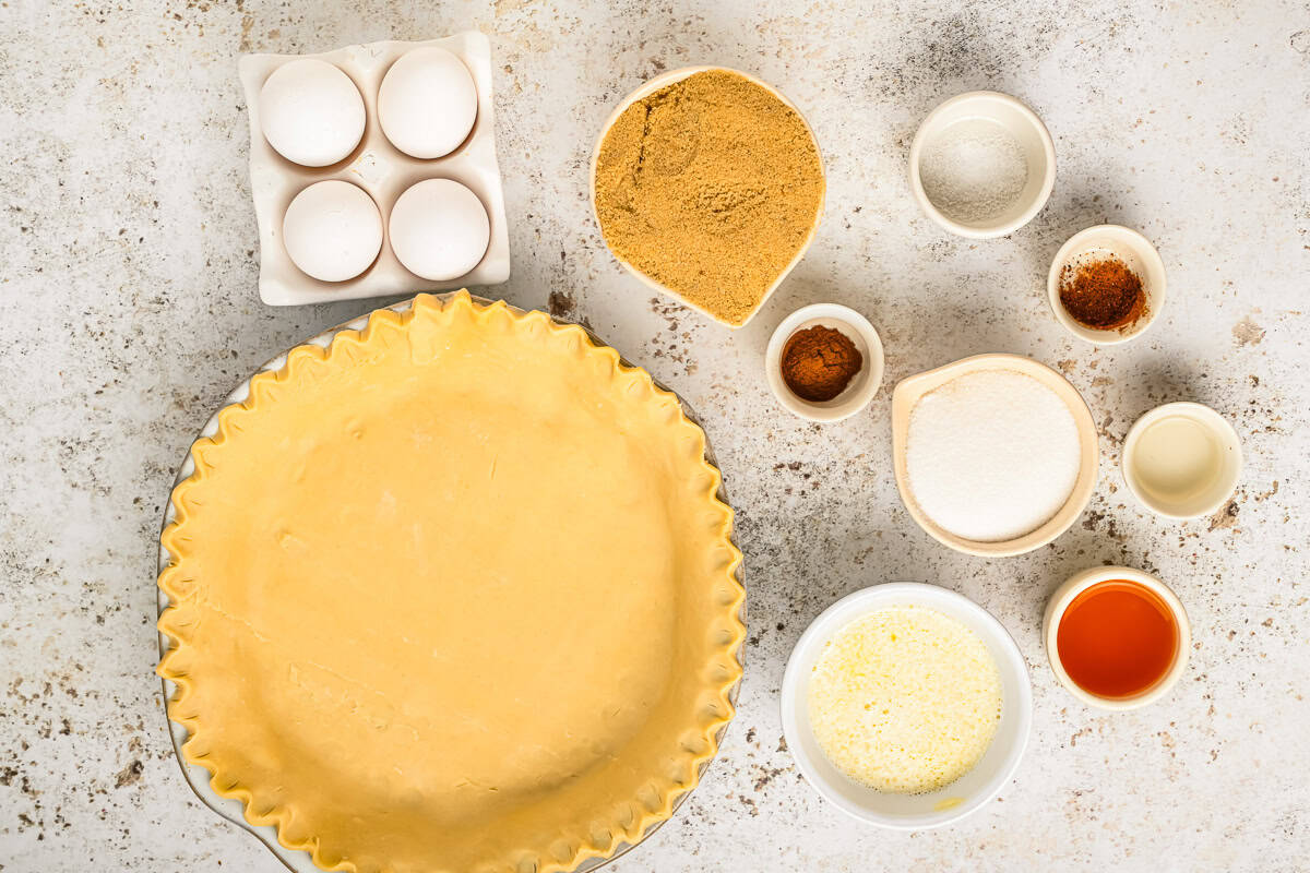 portioned ingredients for vinegar pie filling next to a crimped pie crust in a pie pan.