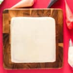 a crumb-coated square peppermint cake on a wooden cutting board.