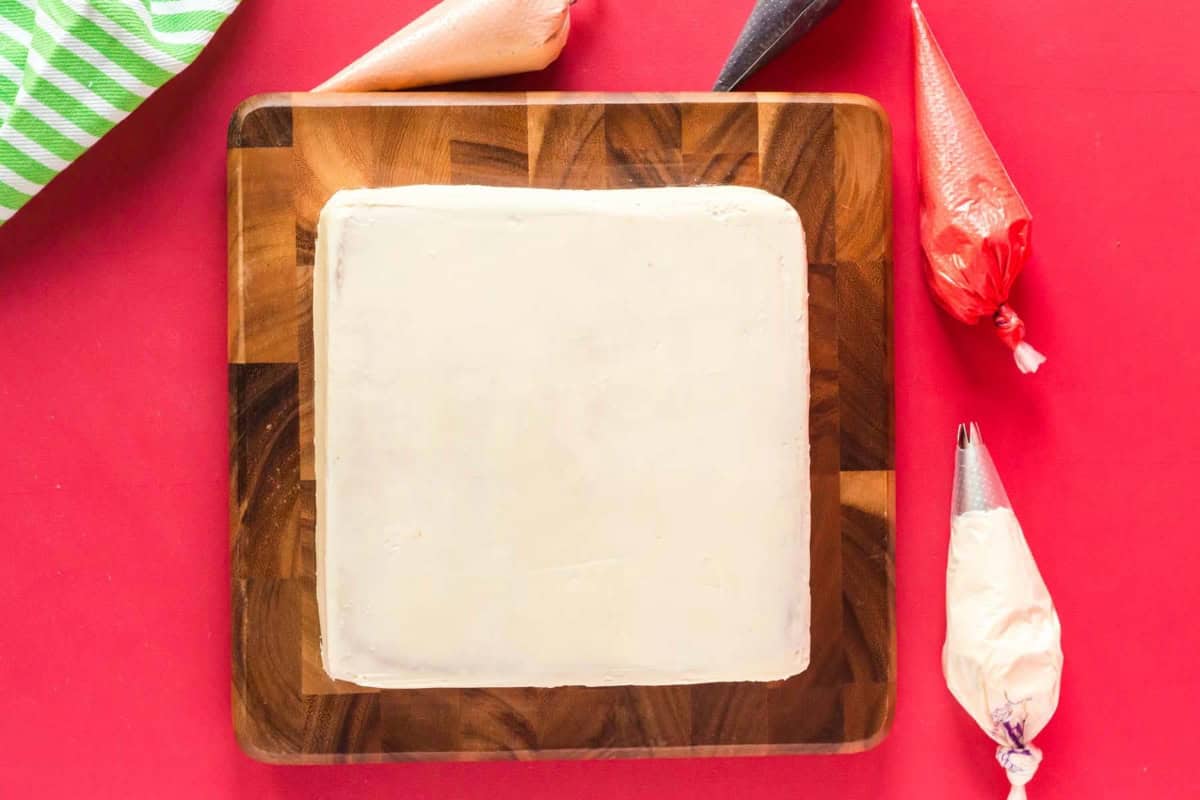 a crumb-coated square peppermint cake on a wooden cutting board.