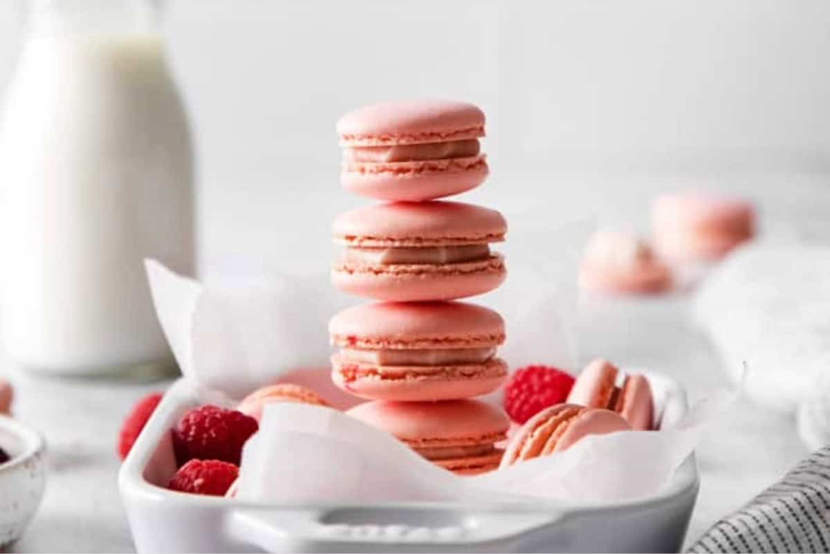 A stack of raspberry macarons in a white dish.