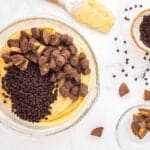 chopped peanut butter cups and chocolate chips over peanut butter fluff in a glass bowl.