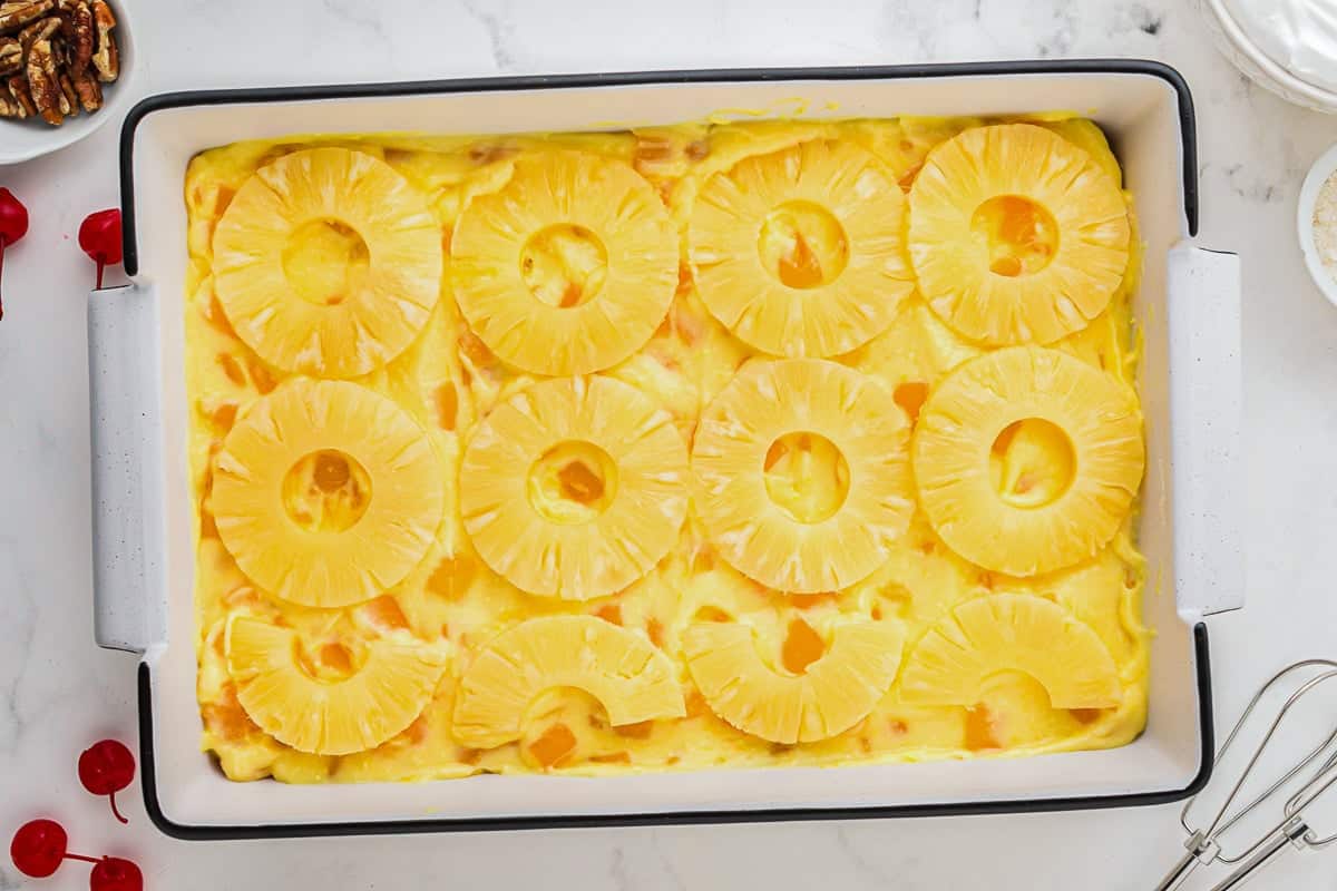 pineapple rings over mango pudding in a baking dish.