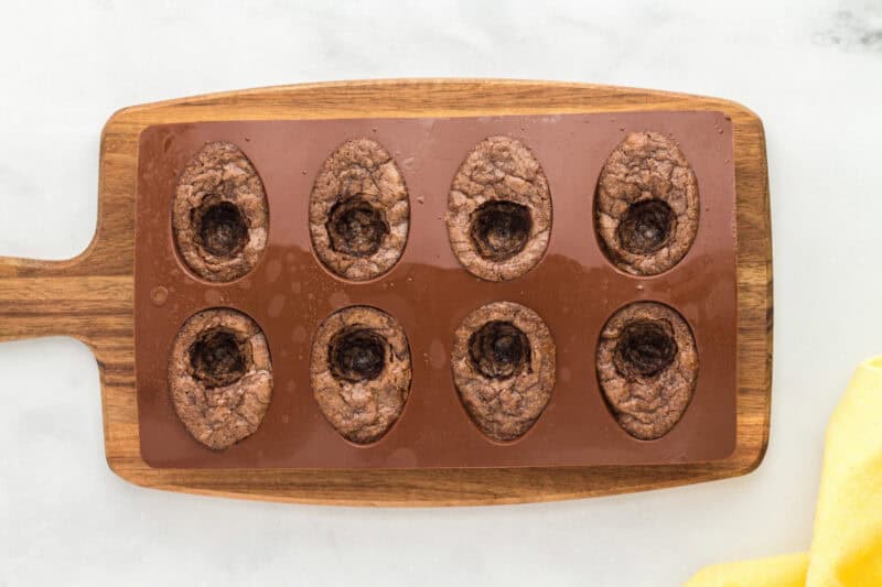 baked brownies with a yolk-shaped circle scooped out of the center in a silicone mold.