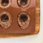 closeup of baked brownies with a yolk-shaped circle scooped out of the center in a silicone mold.