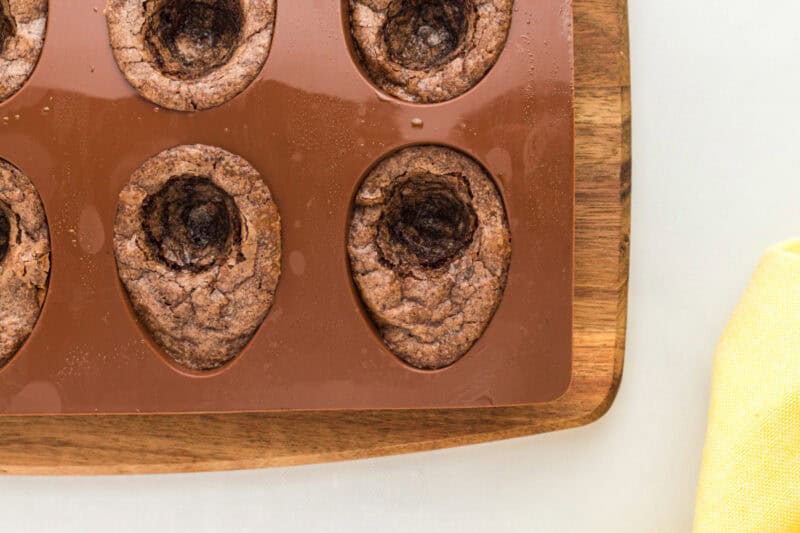 closeup of baked brownies with a yolk-shaped circle scooped out of the center in a silicone mold.