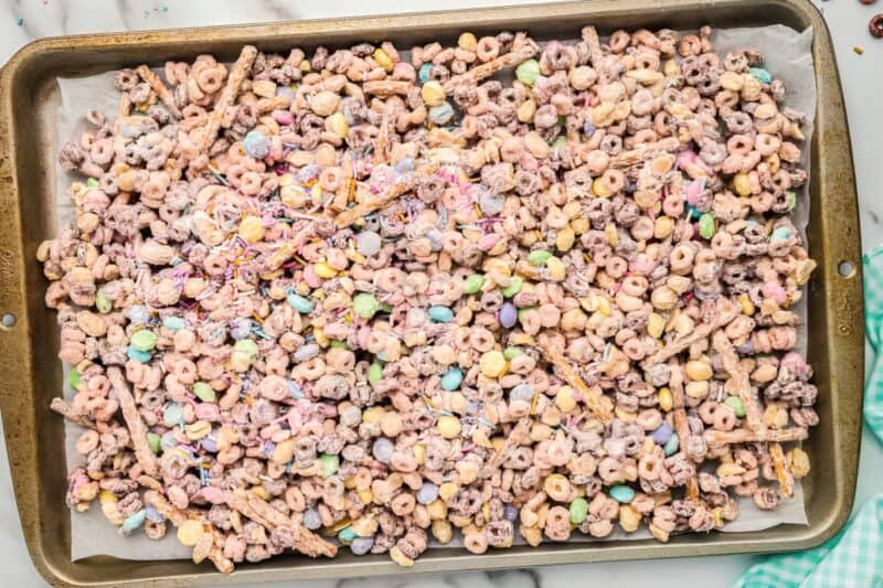 White chocolate coated bunny bait snack mix spread out on a baking tray.