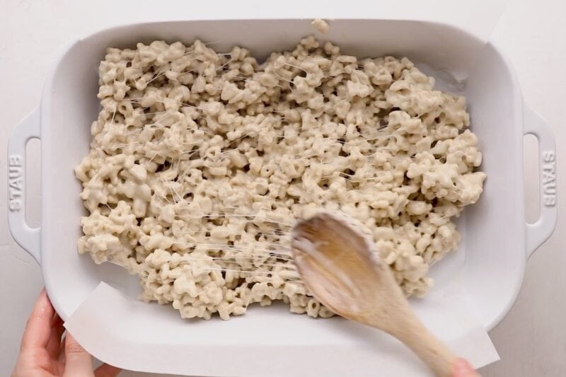 Spreading a marshmallow cereal mixture into a baking pan.