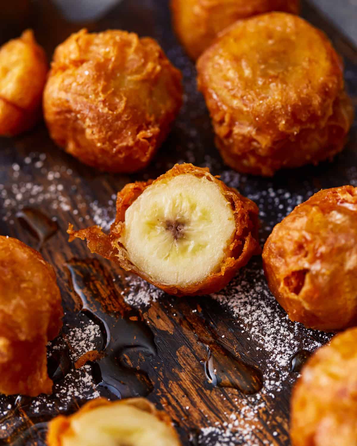 Fried bananas dusted with powdered sugar and one cut in half.