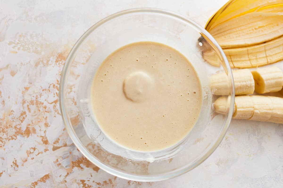 A banana piece being dipped in batter.