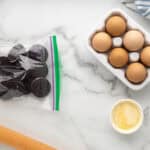 Oreos in a ziplock bag next to a rolling pin.