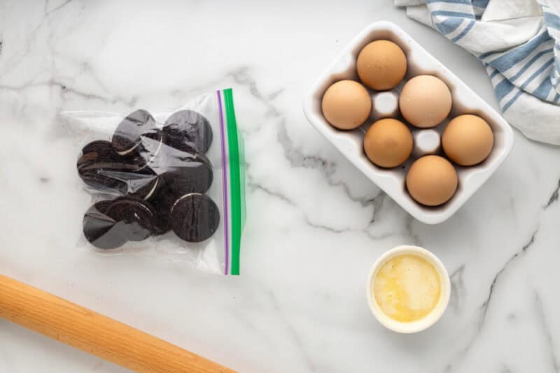Oreos in a ziplock bag next to a rolling pin.