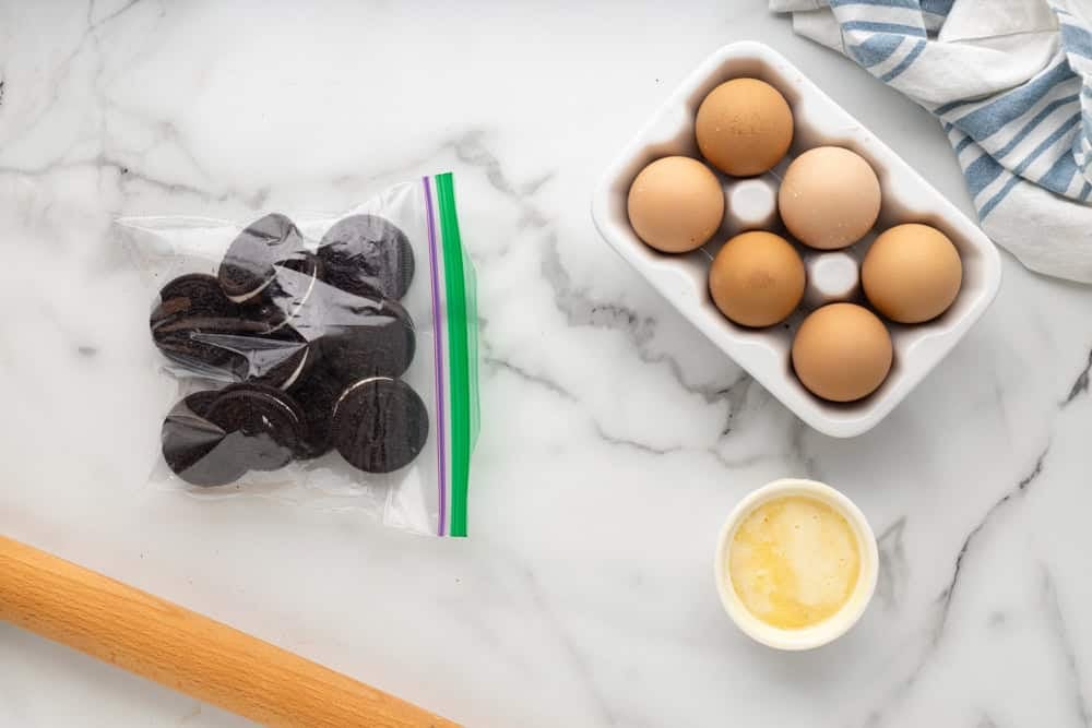 Oreos in a resealable bag, next to eggs and a rolling pin.