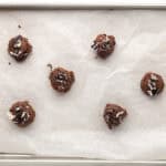 Cookie dough rolled into balls on a lined baking sheet.