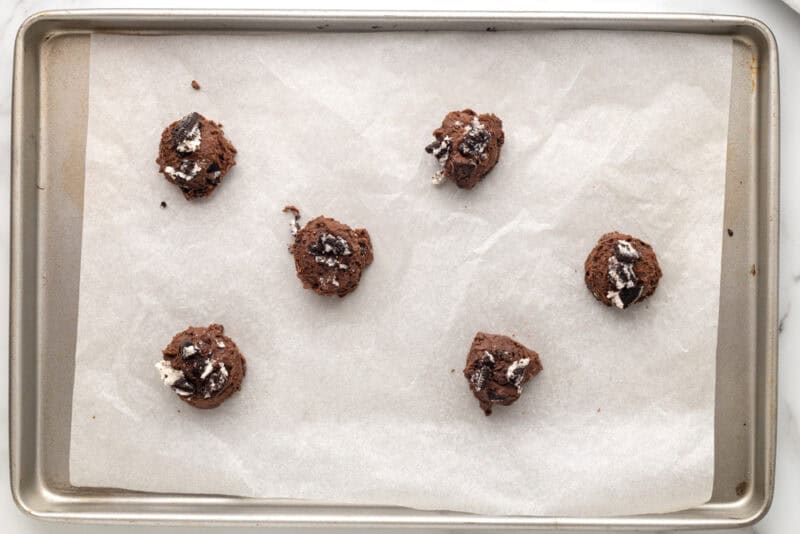 Cookie dough rolled into balls on a lined baking sheet.
