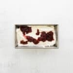 Ice cream pored into a loaf tin with jam added on top.