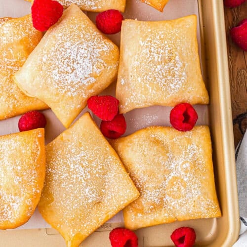 Sopapillas and fresh raspberries on a baking sheet.