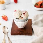 Scoops of strawberry cheesecake ice cream served in a small bowl.