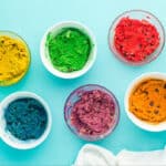 Colored cookie dough in separate bowls.